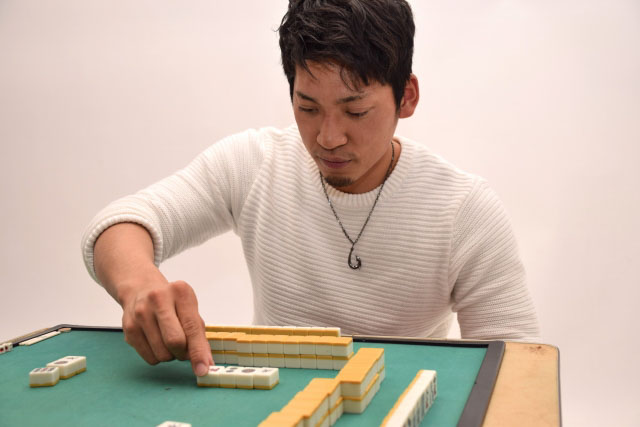 A man playing Japanese mahjong at a special mahjong table.