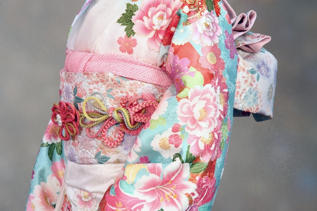 Close up image of a formal kimono, with pink flower patterns and different details