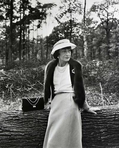 Gabrielle Coco Chanel sitting next to a Chanel 2.55 bag