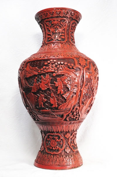A red lacquer vase with detailed carved ornaments