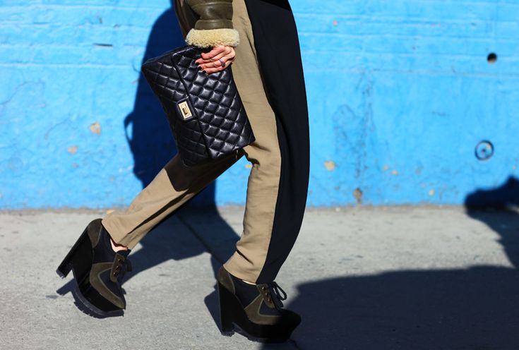 A person walking and holding a Chanel 2.55 Reissue with their hands
