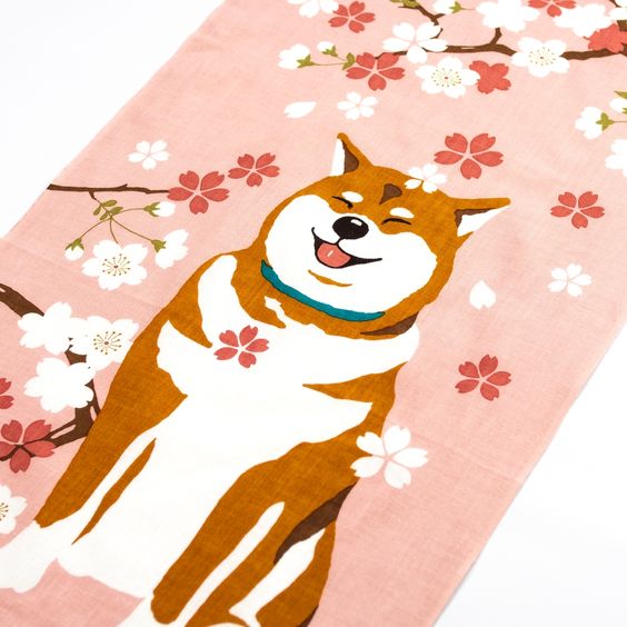 A tenugui towel with a smiley Shiba-inu dog printed on it