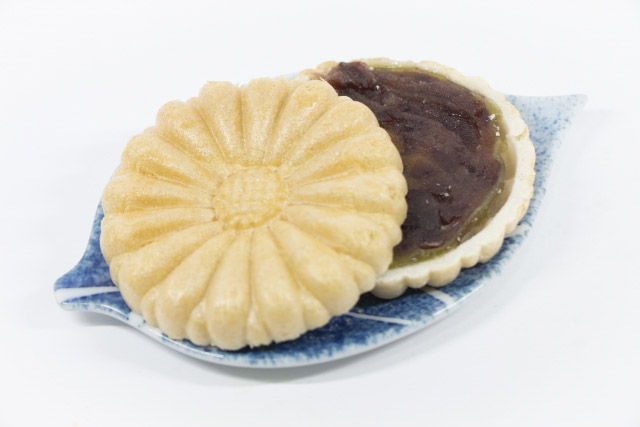 A monaka wafer on a leaf shaped small a plate split in half showing its filling of anko.