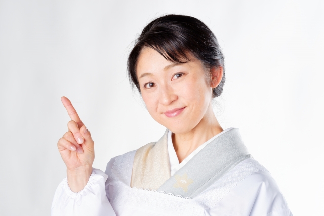 A female wearing a light colored kimono point her indicator finger up
