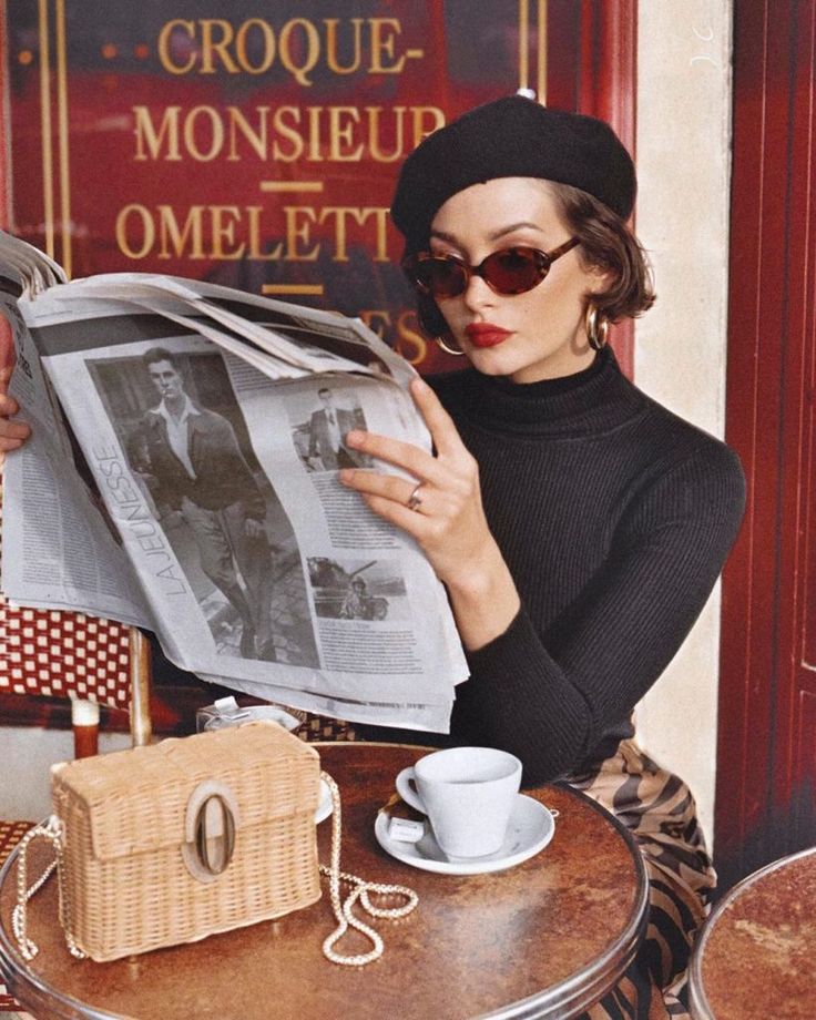 Female wearing a hat, sitting at a cafe reading the newspaper