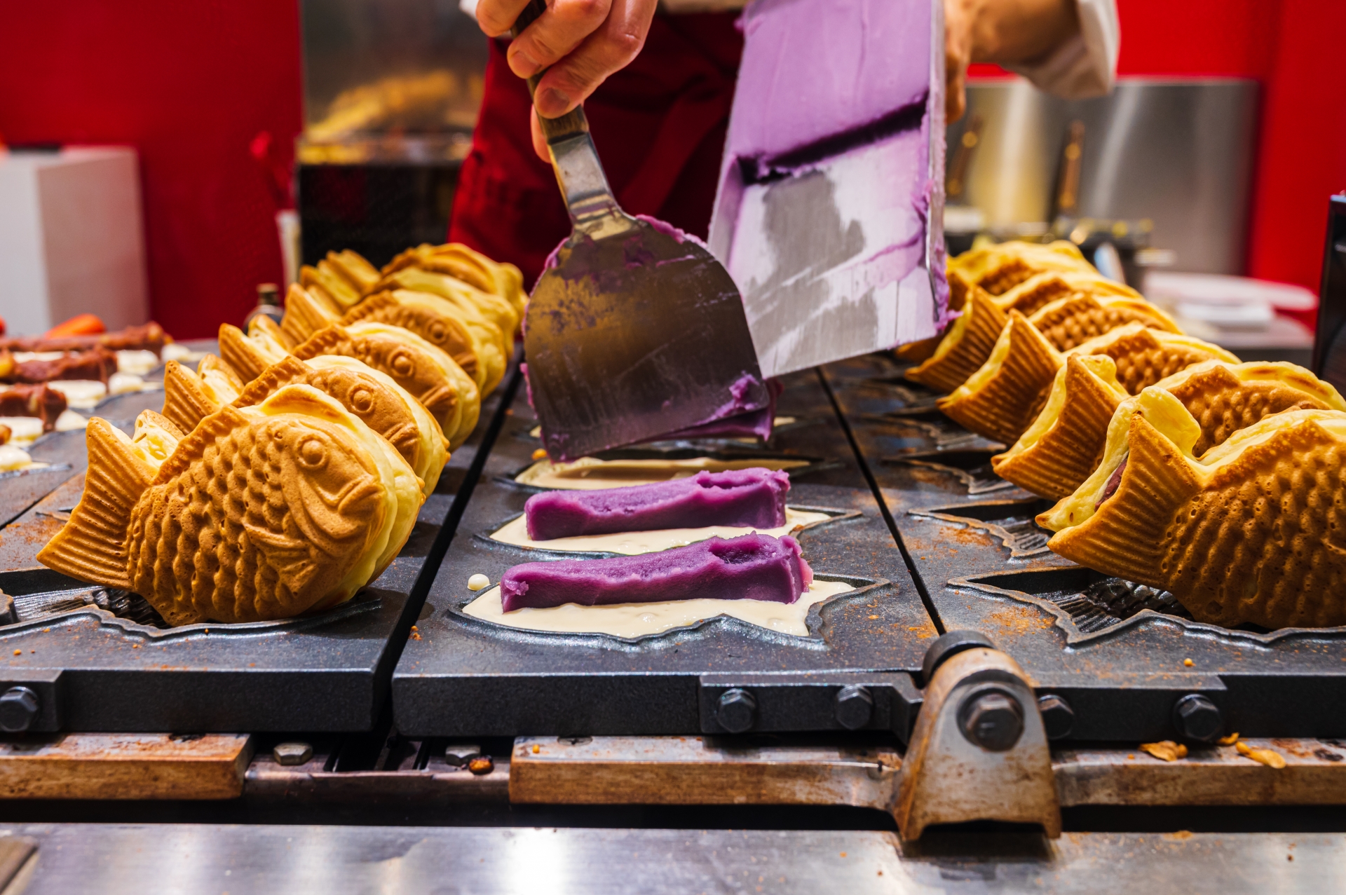 A worker preparing the Japanese sweet cake called Taiyaki with sweet potato paste inside