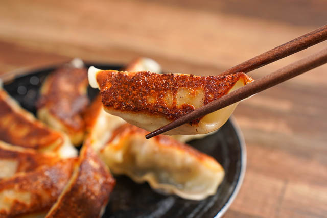 A pair of chopsticks with crispy yaki gyoza 