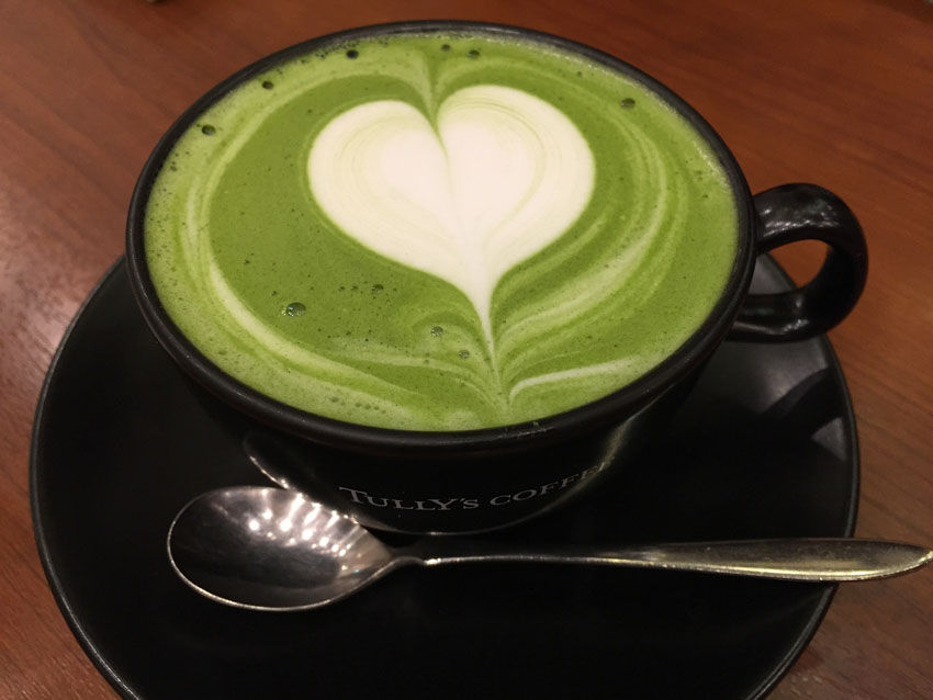 A cup of matcha latte with heart shaped latte art