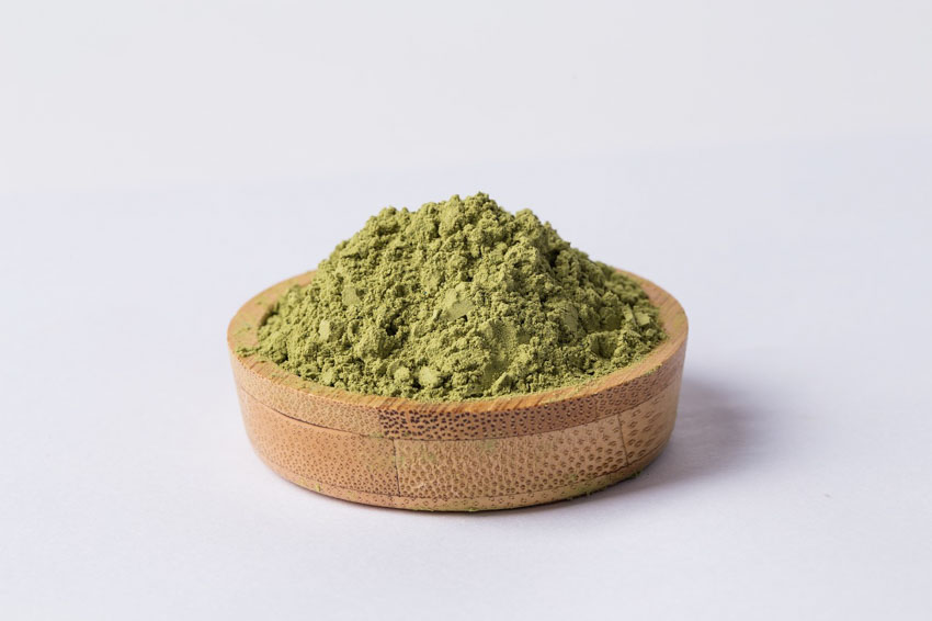 A wooden plate filled with matcha powder.