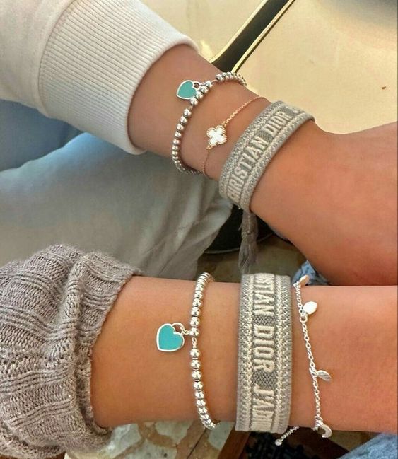 Two people showing their matching high-brand bracelets 