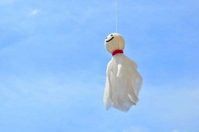 A hanging Teru Teru Bozu against an almost clear blue sky 