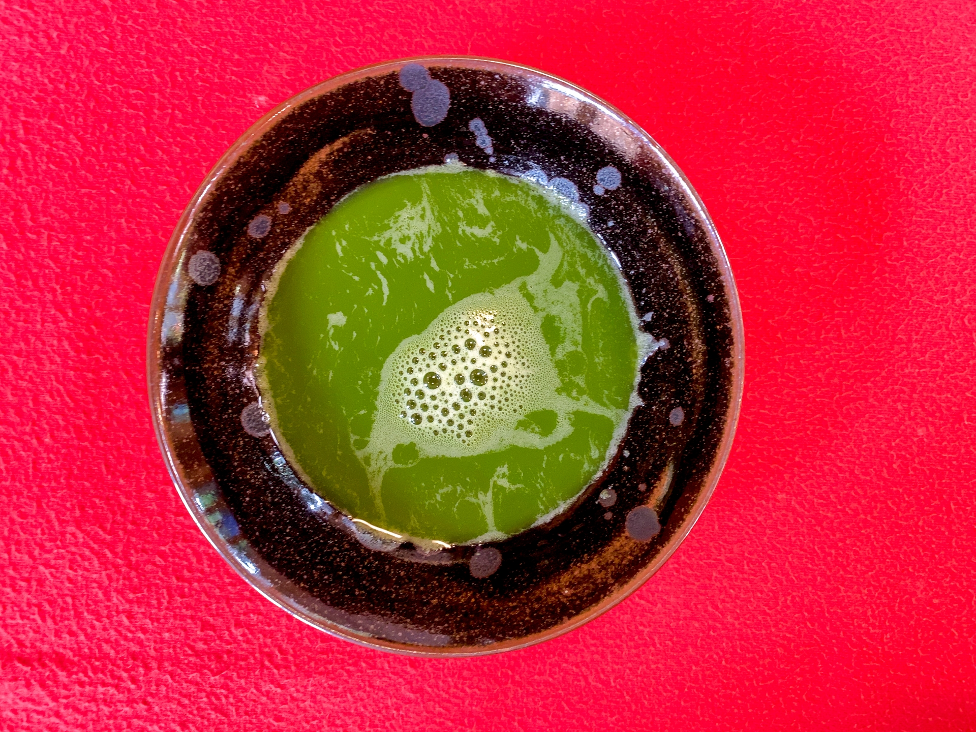 A bowl of freshly whisked matcha green tea viewed from above