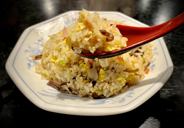 Close up plate with fried rice on it with a spoon upfront of the image