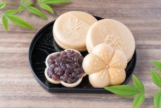 Three pieces of monaka wafers on a small tray. One monaka with the top off to reveal the anko filling inside.
